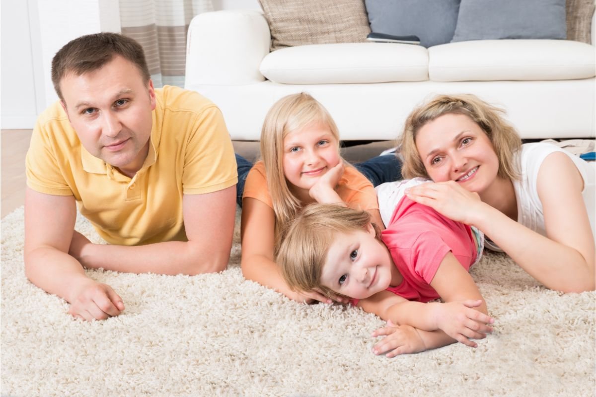 Happy family enjoying time together on pristine white carpet from Carpet & Flooring Warehouse.