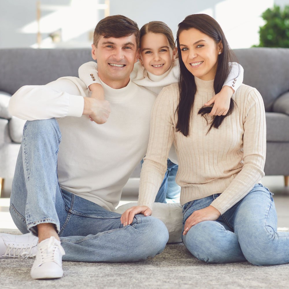 Happy family sitting on carpet flooring provided by Carpet & Flooring Warehouse